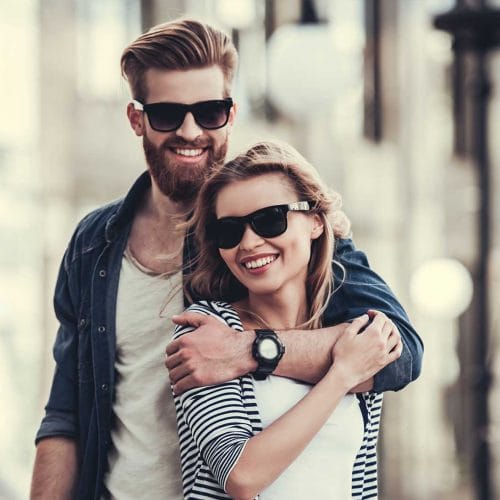 Happy woman and man with glasses, both smiling broadly.