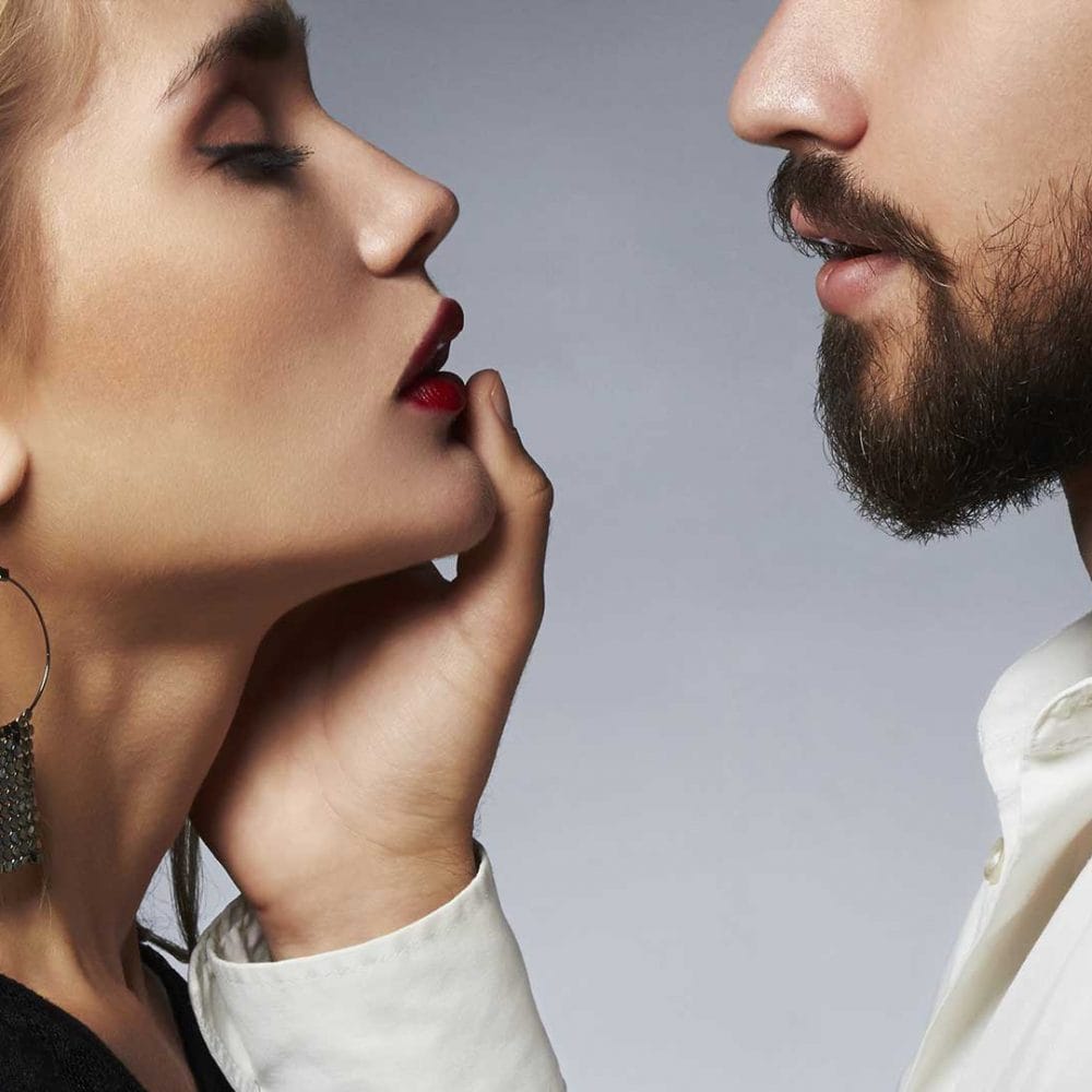 Man and woman close together, man touching her lips.