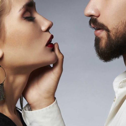 Man and woman close together, man touching her lips.