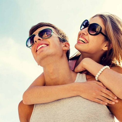 A woman and man smiling happily, both wearing glasses.